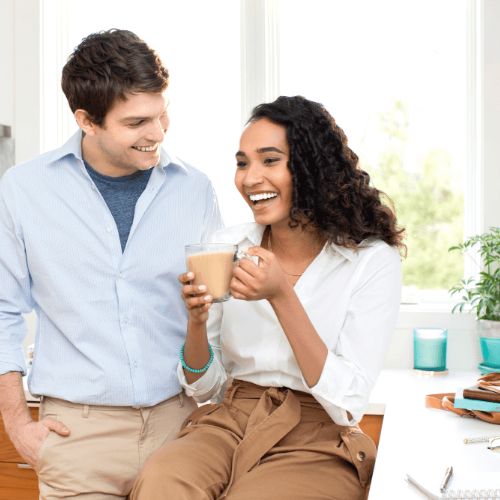 couple drinking coffee in kitchen while laughing
